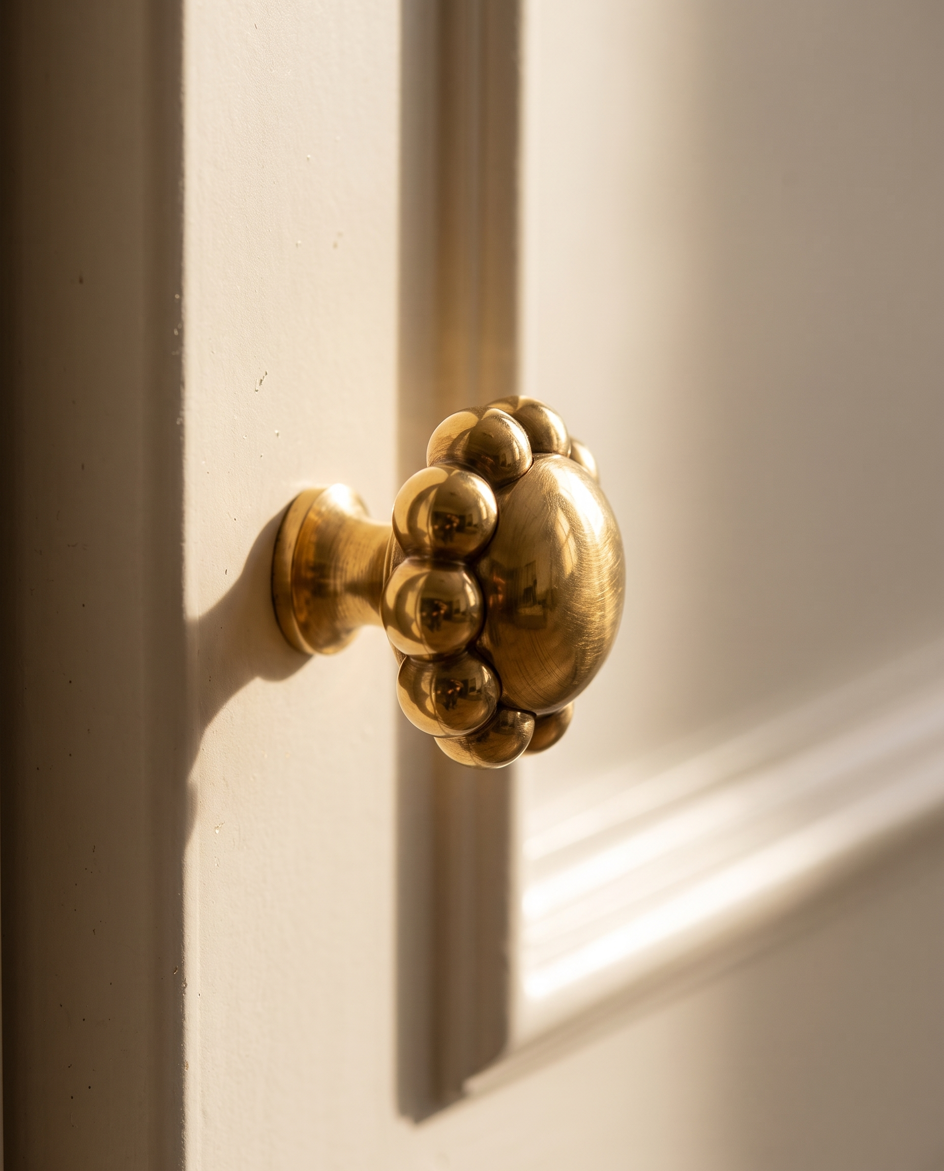 Brass Round Knobs and T-Bar Pulls, Solid Brass — single brass knob, cabinet face, warm side-light finish macro detail