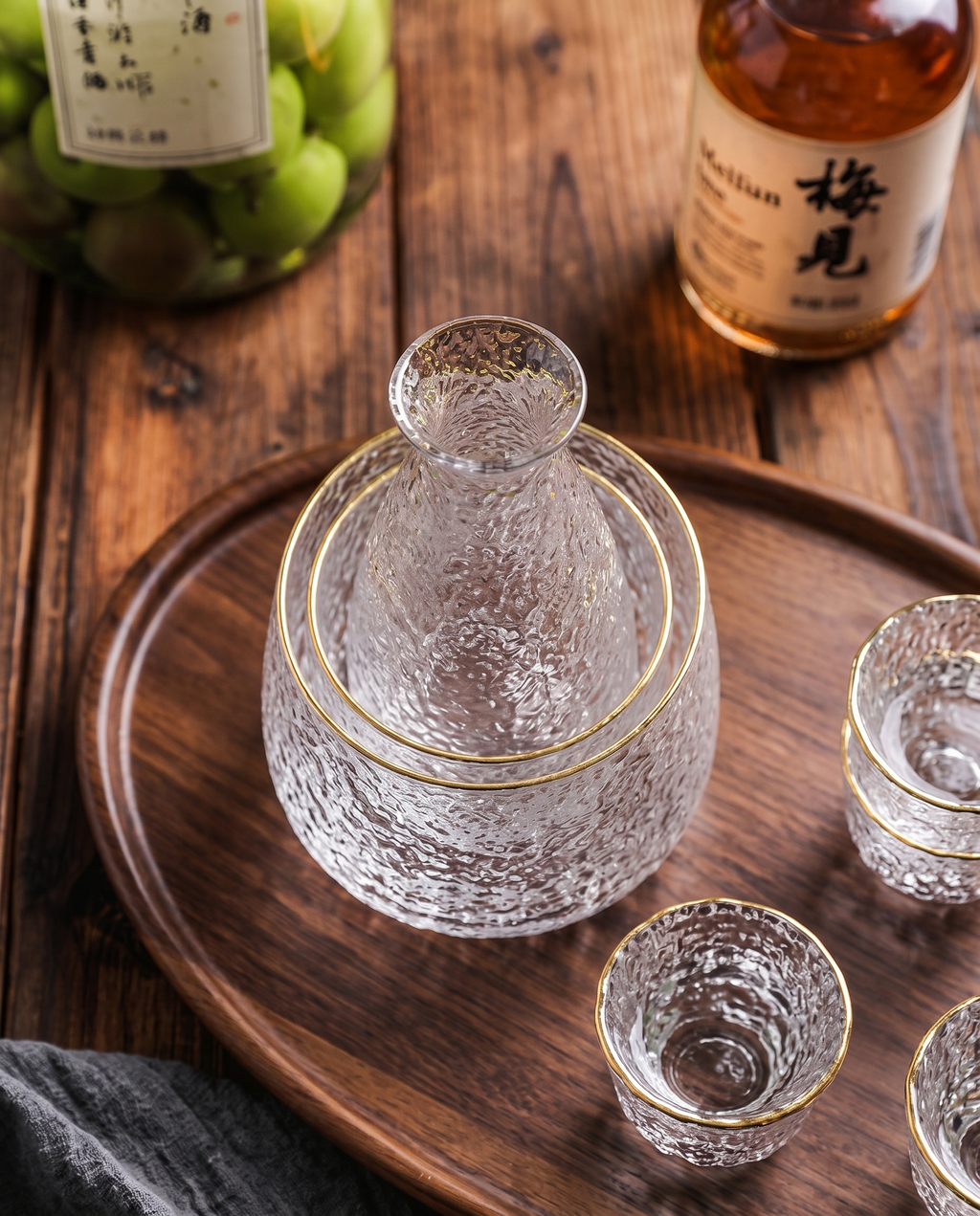 Glass Sake and Bar Serving Set, 6-Piece — alternate top-down angle, dark wood surface, glass carafe and glasses