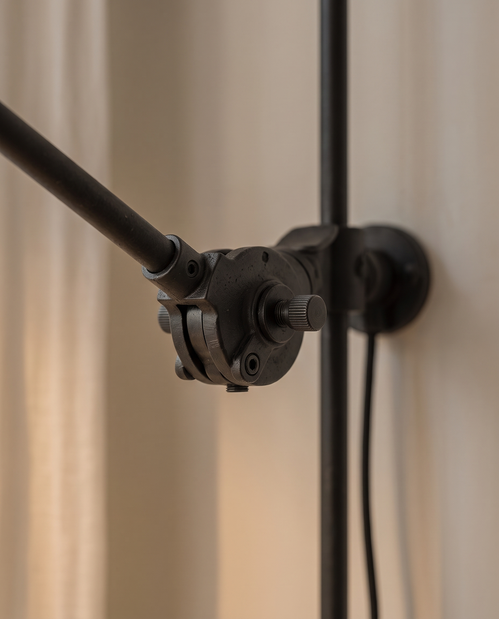Black Iron Swing Arm Wall Light, Adjustable — macro detail of the matte black iron pivot joint, warm side light revealing finish