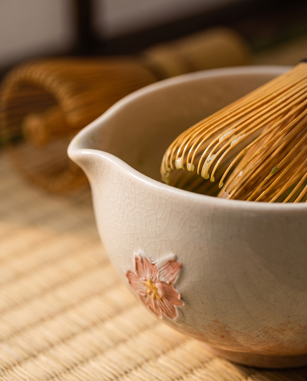 Cherry Blossom Matcha Ceremonial Set — macro detail, warm side light, painted sakura glaze on ceramic bowl and bamboo whisk tines