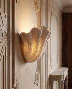 Gypsum Shell LED Wall Sconce — three-quarter side angle, warm plaster wall with French moulding, sculptural shell form