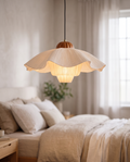 Pleated Petal Fabric Pendant Light, Cream — hero shot hanging in a soft modern bedroom, layered petal shade with a gentle warm glow