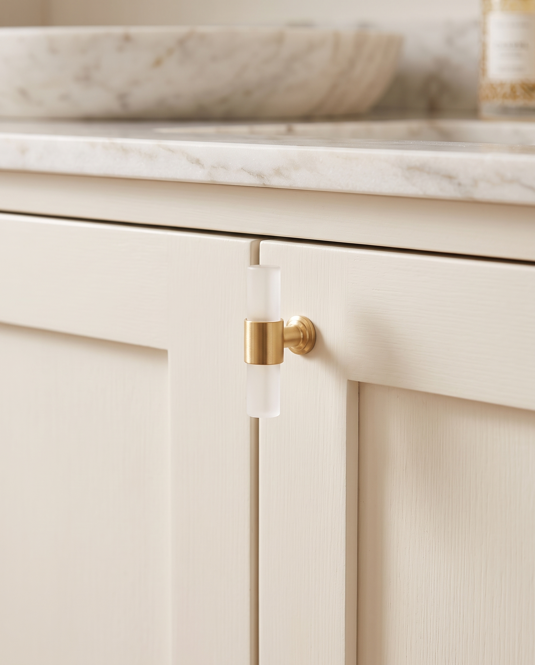 Stone and Brass T-Bar Cabinet Hardware — Crystal White knob, mounted on cream cabinetry, marble vanity