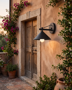 Industrial Iron Outdoor Wall Sconce — placement and scale, mounted beside villa door and stone trim with greenery at dusk